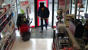 Mężczyzna w drzwiach wejściowych do sklepu drogeryjnego -ma zamazana komputerowo twarz.