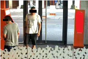 Na zdjęciu widzimy  osoby, dwóch mężczyzn  - wchodzących do pomieszczenia z bankomatem.