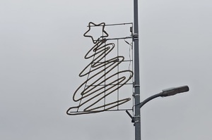 Na zdjęciu wisząca na słupie latarni ulicznej ozdoba w postaci choinki z gwiazda na czubku.