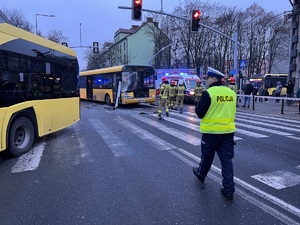 Na zdjęciu widzimy ulicę ba której zderzyły się dwa autobusy. Widać policjanta i w tle strażaków.