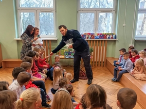 Na zdjęciu policjant rozdaje dzieciakom odblaski.