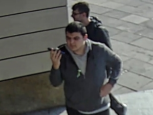 Na zdjęciu widzimy dwóch młodych mężczyzn, jeden z nich rozmawia przez telefon.