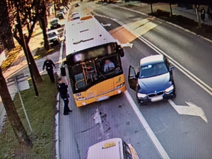 Na zdjęciu widać zatrzymany na ulicy autobus. Obok drzwi stoją policjanci.