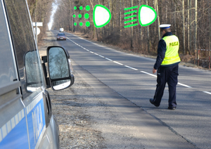 Na zdjęciu policjant drogówki zatrzymuje auto.