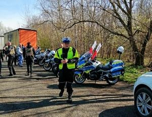 Na zdjęciu widzimy zaparkowane kilka motocykli, w tym na pierwszym planie - policyjny ścigacz do którego zmierza policjant.