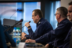 Na zdjęciu widzimy siedzącego przed mikrofonem generała policji, który przemawia.