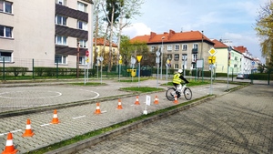 Na zdjęciu widzimy chłopca na rowerze, który pokonuje przeszkodę w postaci zamkniętego pasa ruchu.