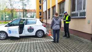 Na zdjęciu widać policjanta ruchu drogowego wraz z uczestnikiem konkursu, który sprawdza jak w pojeździe działają światła pozycyjne.