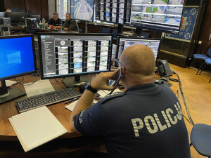 Na zdjęciu widzimy policjanta obserwującego monitory z podglądem sytuacji na drogach.