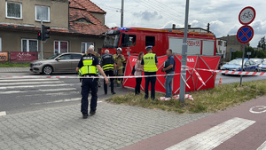 Na zdjęciu grupa policjantów i strażaków stojących przy parawanie na skrzyżowaniu.