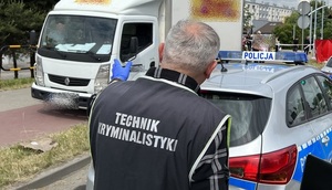 Na zdjęciu technik kryminalistyki wskazuje na samochód dostawczy, obok stoi radiowóz.