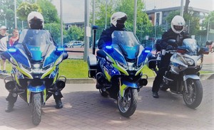 Na zdjęciu możemy zobaczyć trzy motocykle policyjne wraz z policjantami ubranymi w mundur służbowy oraz kaski motocyklowe