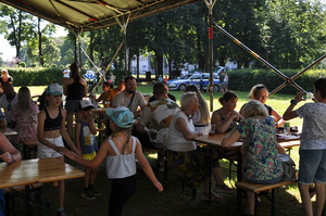 Zdjęcie z pikniku policyjnego, zrobione na terenach zielonych przy Klubie Garnizonowym w Gliwicach, na pierwszym planie widzimy pod namiotem biesiadujących ludzi.