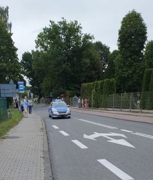 Na zdjęciu widoczny oznakowany radiowóz policyjny jadący ulicą.