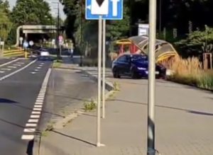 Na zdjęciu przystanek autobusowy i stojący w nim samochód marki BMW