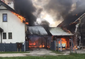 Na zdjęciu widzimy dwa budynki jednorodzinne objęte płomieniami i dymem.