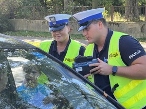 Policjant i policjantka okazują kierującej ekran miernika prędkości.