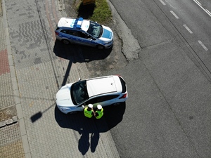 Dwoje policjantó kontroluje samochód - widok z lotu ptaka.