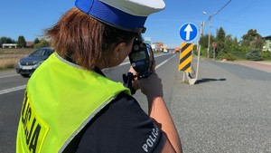 Policjantka celująca miernikiem prędkości w nadjeżdżający samochód.