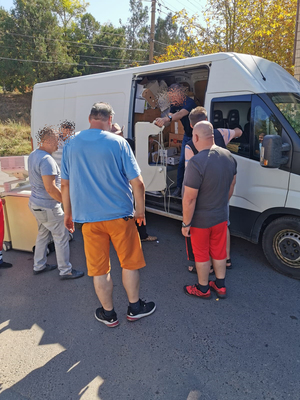 Kilku mężczyzn rozładowuje transport humanitarny.