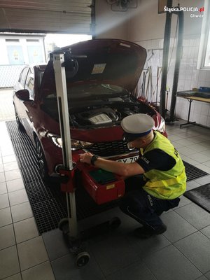 Na zdjęciu policjant sprawdzający światła w samochodzie osobowym.