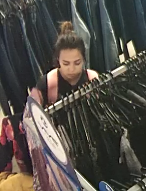 Na zdjęciu młoda kobieta około 20-letnia wśród wieszaków z ubraniami.