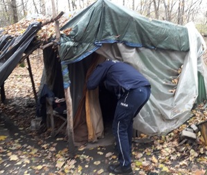 Na zdjęciu policjant zaglądający do szałasu