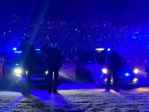 Na zdjęciu - po zmroku stoją przed swoimi pojazdami od lewej: strażacy, strażnicy miejscy i policjanci - oddają honor poległym - stoją w postawie baczność.
