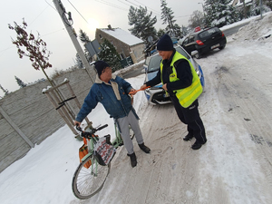 Na zdjęciu policjantka drogówki wręcza odblask rowerzyście.