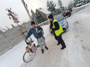 Na zdjęciu policjantka drogówki wręcza odblask rowerzyście.