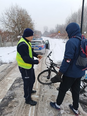 Na zdjęciu policjant drogówki wręcza odblask rowerzyście.