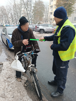 Na zdjęciu policjant drogówki wręcza odblask rowerzyście.