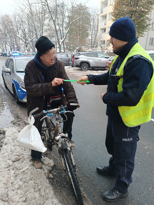 Na zdjęciu policjant drogówki wręcza odblask rowerzyście.