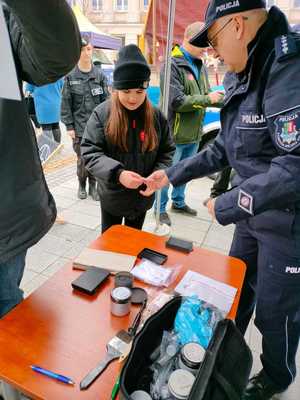 Na zdjęciu policjant pokazujący dziewczynce przybory technika kryminalistyki.