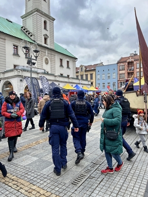 Na zdjęciu gliwicki rynek widać ratusz i wiele osób w otoczeniu. W centrum zdjęcia trzyosobowy patrol policyjny.