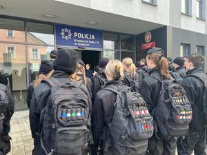 Na zdjęciu grupa młodzieży szkolnej w mundurach z plecakami stoja przed komisariatem III w Gliwicach