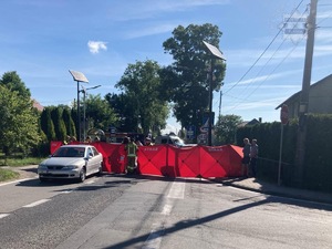 Zdjęcie przedstawia rozłożony parawan koloru czerwonego na środku ulicy, oraz stojący po lewej stronie samochód osobowy.