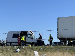 Na zdjęciu samochód bus z rozbitym przodem stoi za Tirem. Wokół policjanci