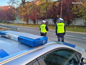 Na zdjęciu widać dwóch policjantów drogówki pilnujących bezpieczeństwa na drodze.