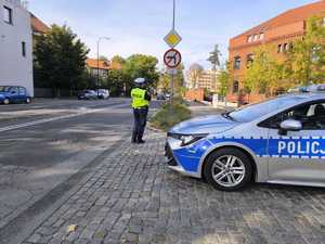 Na zdjęciu policjantka przy radiowozie - mierzy prędkość