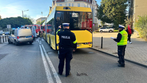 Na zdjęciu dwaj policjanci prowadzą działania przy autobusie komunikacji miejskiej. W tle oprócz autobusu pojazdy wszystkich służb ratunkowych.