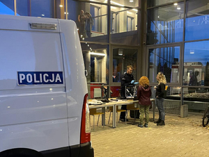 Na zdjęciu policyjny furgon, w tle stoisko i rozmowa policjanta ze zwiedzającymi.