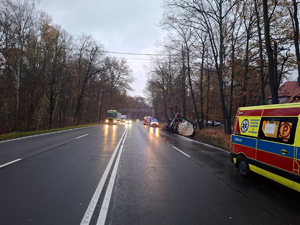 Na zdjęciu droga dwukierunkowa dwupasmowa w każdym kierunku. Widać ciężarówkę cysternę w rowie i inne samochody przemieszczające się.