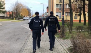 Na zdjęciu dwóch umundurowanych policjantów w patrolu na osiedlowej uliczce