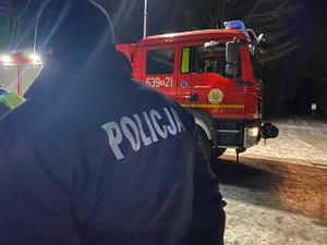 Na zdjęciu policjant na tle wozu strażackiego