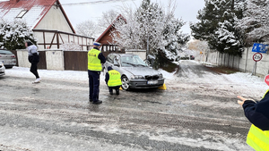 Na zdjęciu widać szerszy plan i centralnie rozbity samochód marki BMW. Widać policjantów pracujących na miejscu