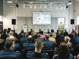 Sala pełna osób siedzących - wszyscy patrzą na ekran.