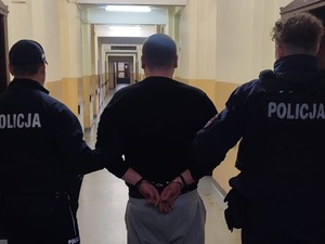 policjanci prowadzą zatrzymanego mężczyznę korytarzem