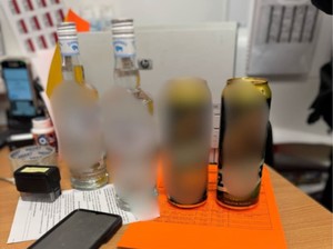 Na stole stoi alkohol, leży telefon i dowód osobisty