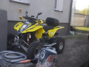 Na podwórku przed domem stojący żółty Quad